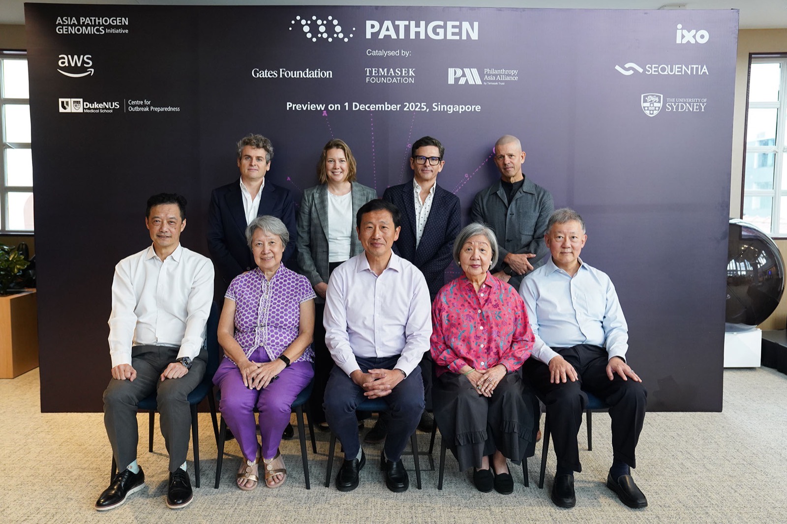 Nine representatives of the partner organisations, five seated and four standing, in front of a backdrop carrying the partner and funder logos above the line “Preview on 1 December 2025, Singapore”.